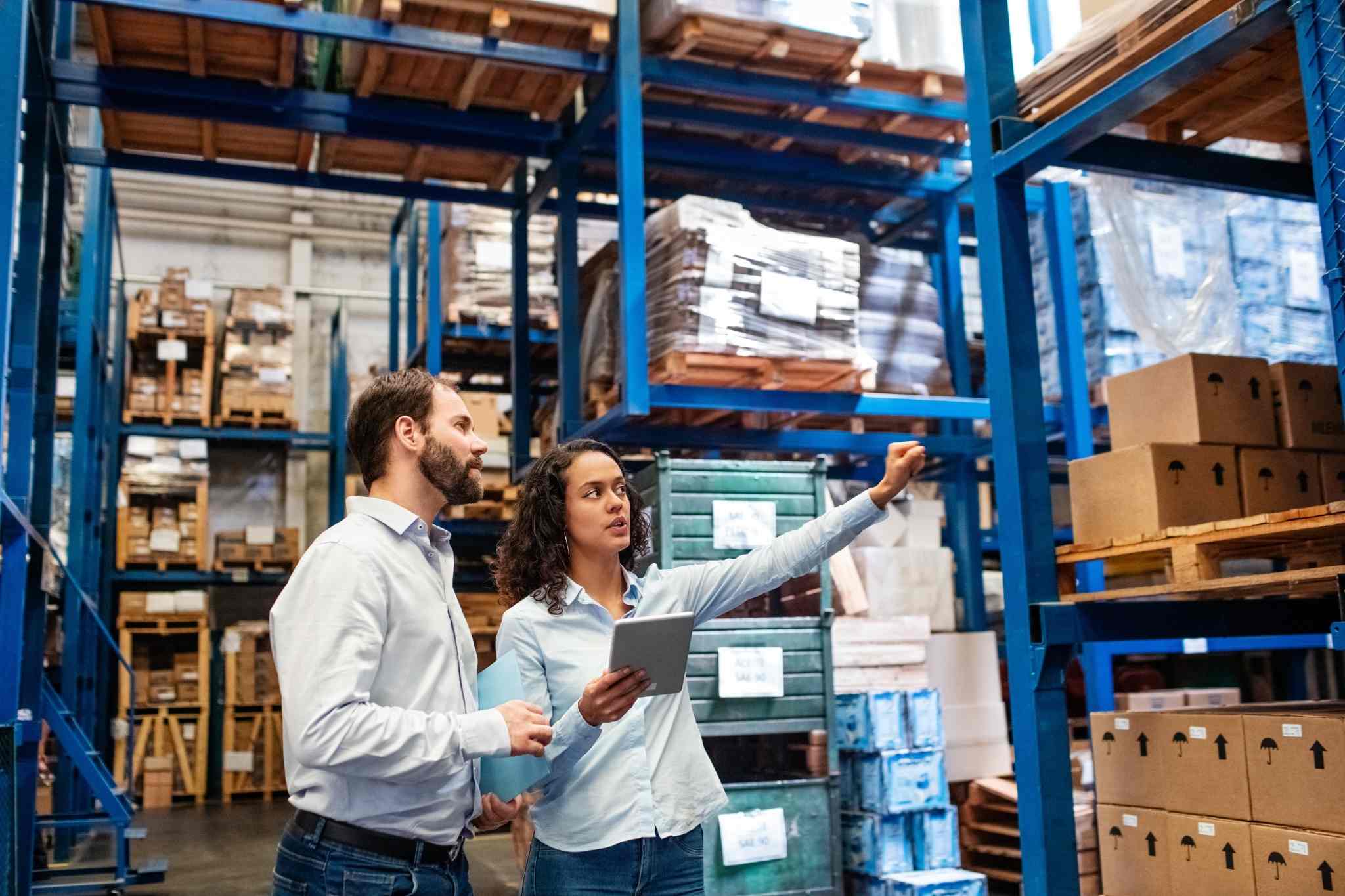 Two warehouse staff checking around