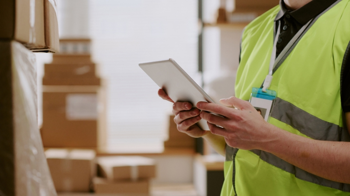 a worker in a bright lime green safety vest holding and using a digital tablet