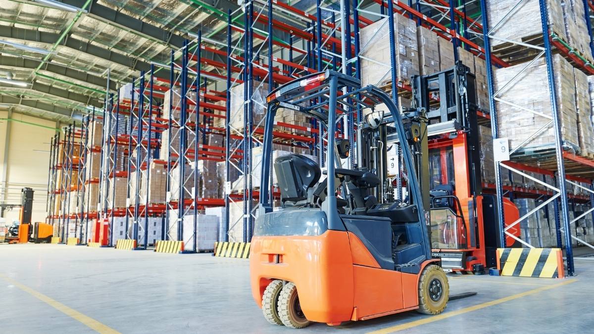 forklift parked on a concrete floor in a massive warehouse